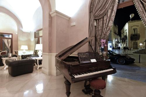 a piano in a lobby with a room with a car at Suite Hotel Santa Chiara in Lecce