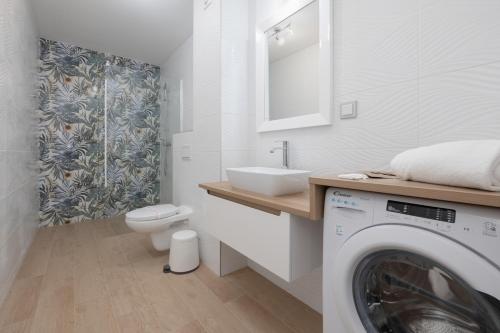 a bathroom with a washing machine and a sink at Jantar Apartamenty Siedem Wysp in Sianozety