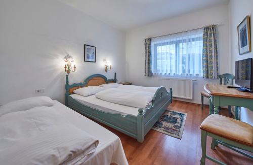 a bedroom with two beds and a desk and a window at Chalet Haider in Saalbach Hinterglemm