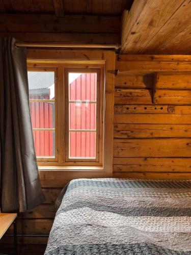 a bedroom with a bed and two windows at Toppøy Rorbuer in Reine