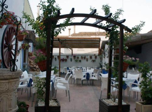 un patio con mesas y sillas blancas y un cenador en Hostal Los Amigos, en La Roda