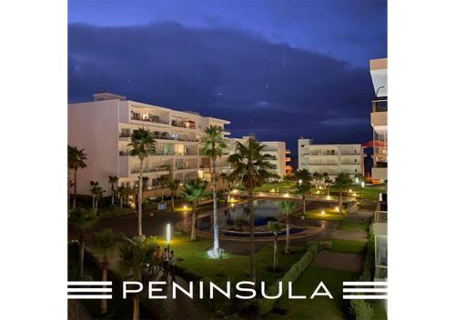 a view of a building with a pool at night at Peninsula Dar Bouazza Superbe appartement en résidence avec piscine activités in Dar Bouazza