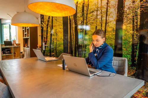 a young girl sitting at a table with a laptop at EuroParcs De Zanding in Otterlo