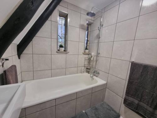 La salle de bains blanche est pourvue d'une baignoire et d'une douche. dans l'établissement Mountain Haven Hideaway, à Buffelspoort