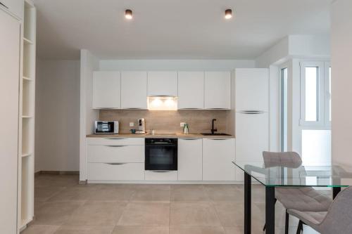 a kitchen with white cabinets and a glass table at Superbe Appartement avec Parking in Malmedy