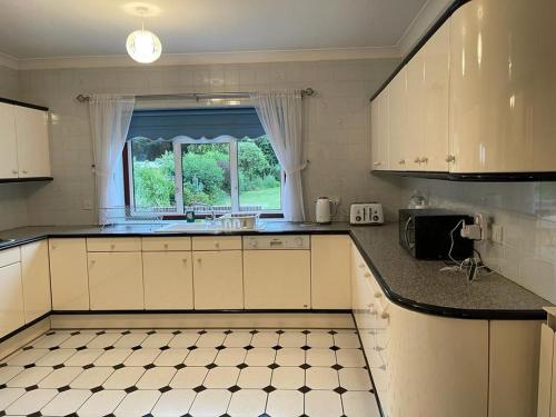 uma cozinha com armários brancos, um lavatório e uma janela em Cheerful 3 bedroom house with off street parking em Bromley