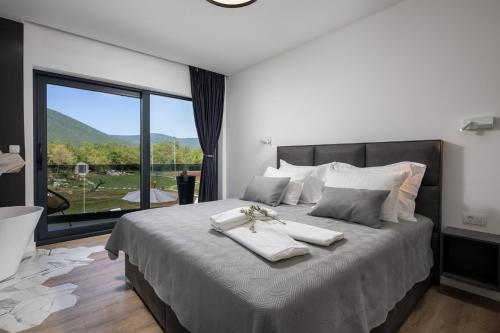 a bedroom with a large bed with a large window at NEW! Villa Nella Foresta with private 66sqm heated pool, Whirlpool, Tennis court, Gym, Billiards, 4 en-suite bedrooms in Radošić