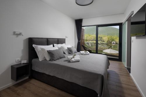 a bedroom with a large bed with a large window at NEW! Villa Nella Foresta with private 66sqm heated pool, Whirlpool, Tennis court, Gym, Billiards, 4 en-suite bedrooms in Radošić