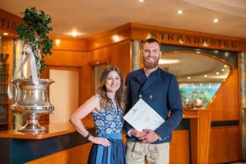 a man and woman standing in front of a store at Promenaden-Strandhotel Marolt in Sankt Kanzian