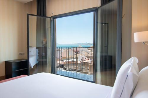 a bedroom with a bed and a large window with a view at Hotel Ibersol Atrio del Mar in Los Alcázares