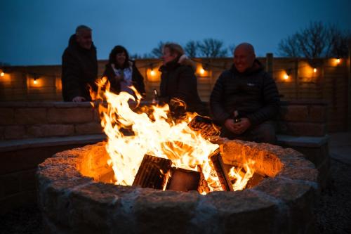 a group of people sitting around a fire pit at Fulshaw Mill Holidays in Stewarton
