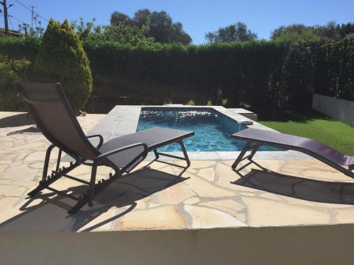a chair and a table next to a swimming pool at Villa L'Adret et sa piscine in Juan-les-Pins