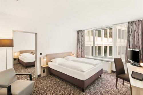a hotel room with two beds and a television at Best Western Plus Hotel Dresden City in Dresden