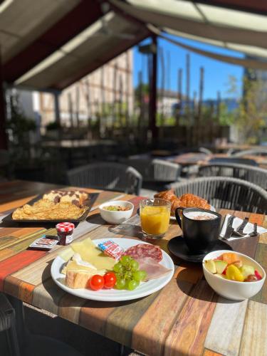 a wooden table topped with plates of food and fruit at The Originals Boutique, Hôtel d'Alsace, Strasbourg Sud in Illkirch-Graffenstaden