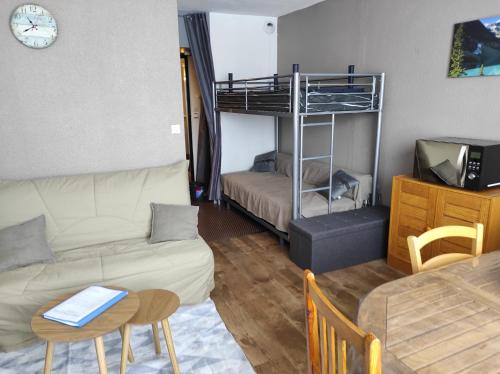 ein Wohnzimmer mit einem Sofa und einem Etagenbett in der Unterkunft La Géla, studio cabine pieds de pistes in Aragnouet