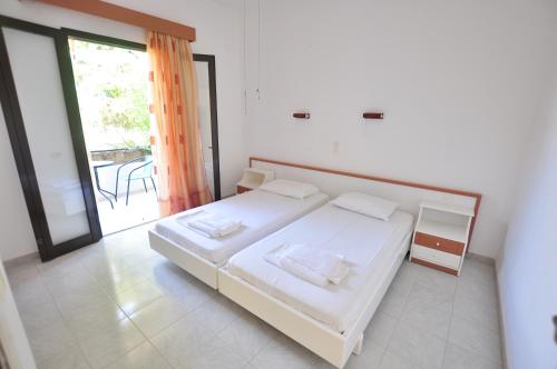 a bedroom with a white bed and a large window at Antigoni Apartments in Acharavi