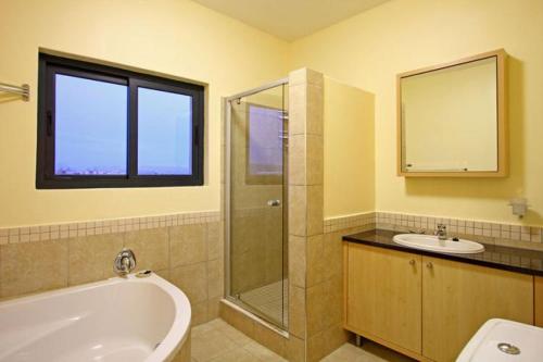 a bathroom with a tub and a sink and a shower at Knightsbridge 407 by Host Agents in Cape Town