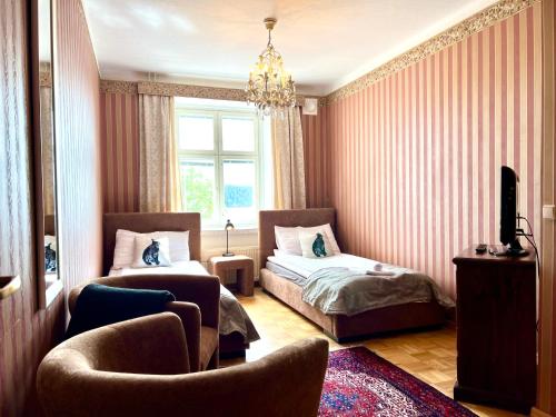 a bedroom with two beds and a chair and a window at Hotel Hospitz in Savonlinna