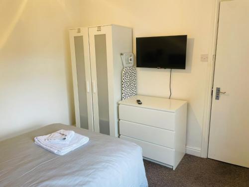 um quarto com uma cama, uma televisão e uma cómoda em 305 High Town Road em Luton