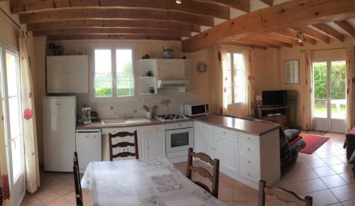 une cuisine avec des armoires blanches et une table dans une pièce dans l'établissement Les pommiers doux, à Lestre