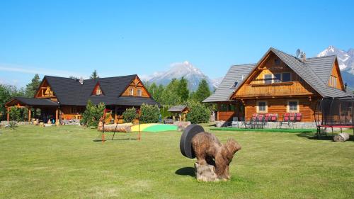 a log cabin with a playground in front of a house at Chaty Rozprávkovo in Vysoke Tatry - Tatranska Lomnica.