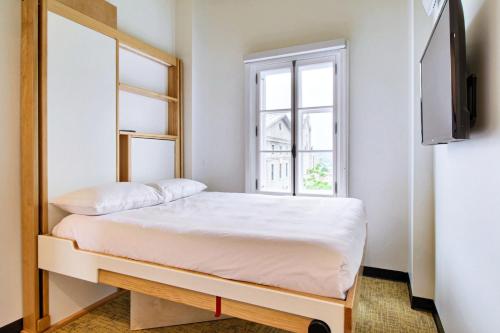 um pequeno quarto com uma cama e uma janela em Hotel AtypiQ em Cidade de Quebec