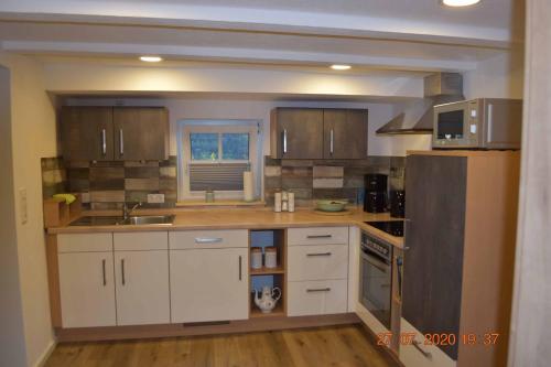 a kitchen with white cabinets and a black refrigerator at Ferienwohnung am Glockenturm in Weißenburg in Bayern