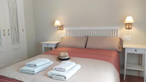 Un dormitorio con una cama con toallas y un sombrero encima. en Sherryflat Laurel, en Jerez de la Frontera