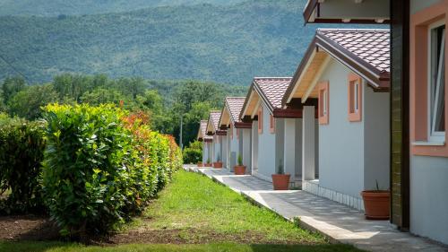 a row of houses with bushes and mountains in the background at Seosko domaćinstvo Jovanović in Danilovgrad