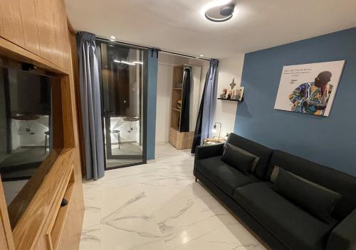 a living room with a black couch and a blue wall at Magnifique appartement Bahia Smir Fnideq Mdiq nord in Fnidek