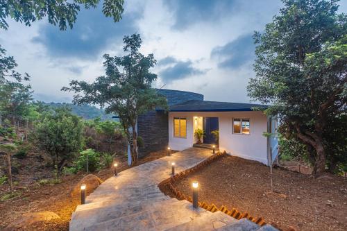 a house with lights on the side of it at SaffronStays Kaia Waters by Kosha Villas, Pawna - Greek style villa with panoramic view of Pawna lake in Kolvan