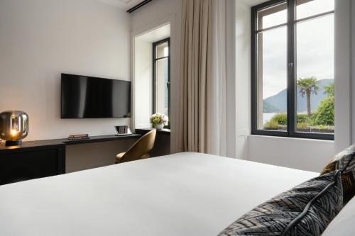 a hotel room with a bed and a tv at MUSA Lago di Como in Sala Comacina