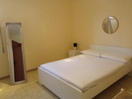 een slaapkamer met een wit bed en een spiegel bij Villetta indipendente in villaggio a 2 passi dal mare in Santa Maria al Bagno