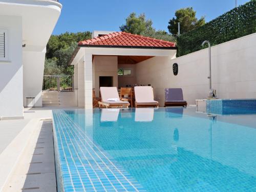 basen z dwoma krzesłami i dom w obiekcie Villa Green Bay w mieście Vela Luka