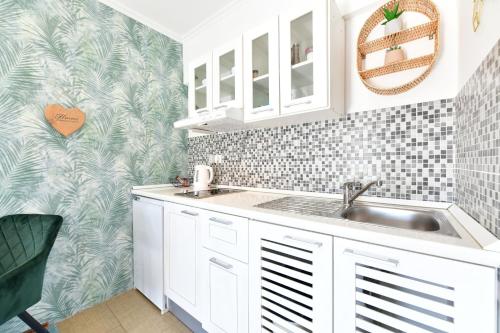 a kitchen with white cabinets and a sink at Apartments Green Park in Rakovica