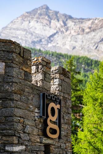 a sign on the side of a stone wall at Boutique Hotel La Gorge in Saas-Fee