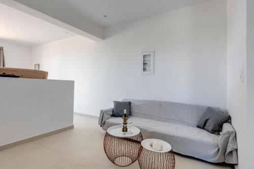 a living room with a couch and two tables at Chrysonisos Suites with Sunset & Seaviews near Kini in Ano Syros