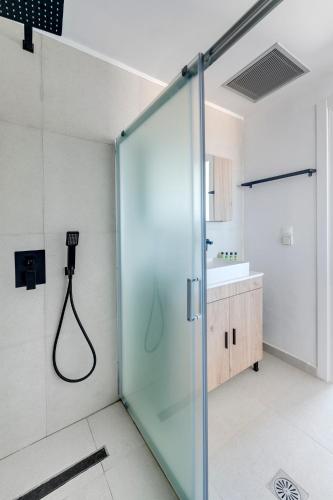 a glass shower in a bathroom with a sink at Chrysonisos Suites with Sunset & Seaviews near Kini in Ano Syros