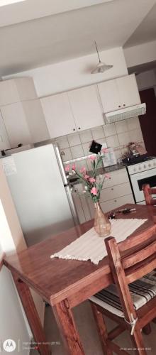 eine Küche mit einem Holztisch mit einer Vase aus Blumen in der Unterkunft Excelente monoambiente in Neuquén