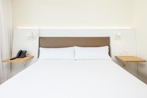 a bedroom with a white bed and a telephone at Playamojácar in Mojácar