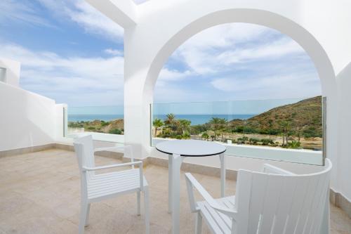 a white room with a table and chairs and the ocean at Playamojácar in Mojácar