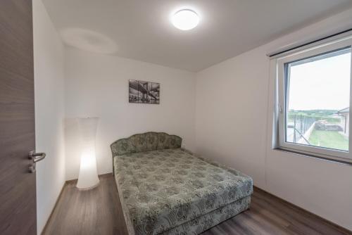 um quarto com uma cadeira e uma janela em Bridgiet Home Apartman em Cserszegtomaj