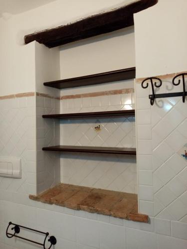 a bathroom with white tiled walls and shelves at La Casetta delle Farfalle in Lanciano