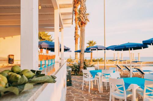 um restaurante com cadeiras e mesas e a praia em Picchio Hotel Pescoluse em Marina di Pescoluse