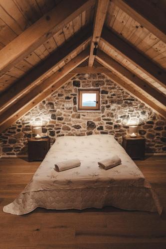 a bedroom with a bed in a stone wall at Villa Terra Meera in Skradin