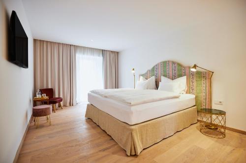 um quarto de hotel com uma cama grande e uma televisão em Boutiquehotel Zum Goldenen Hirschen em Gmunden