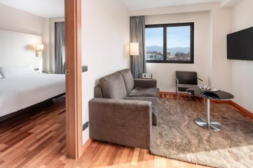 um quarto de hotel com um sofá e uma cama em B&B HOTEL Granada Estación em Granada