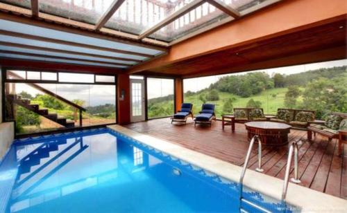 a house with a swimming pool and a deck with chairs at Finca Paraiso Mountain Retreat near San Jose Airport in Birrí