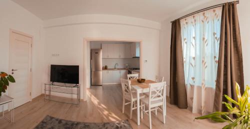 Una sala de estar con mesa de comedor y una cocina. en Solomon Apartments ap 1, en Sângeorgiu de Mureș