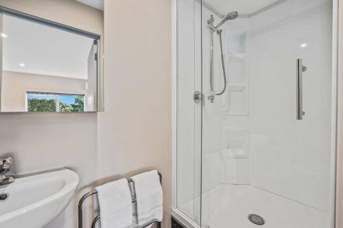 uma casa de banho branca com um chuveiro e um lavatório. em Gatehouse on the Bay - Christchurch Holiday Unit em Christchurch